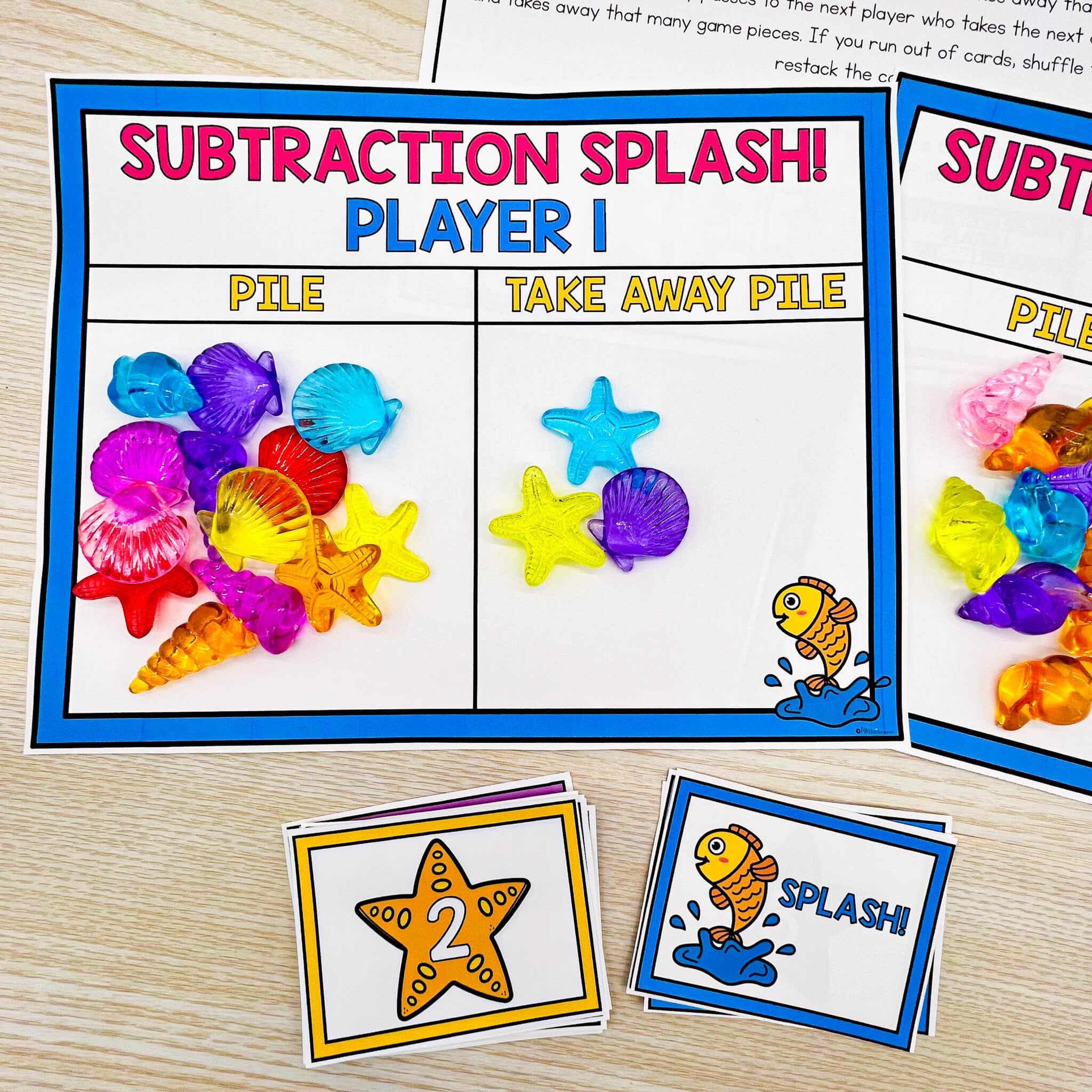 A pile of plastic sea shells are on a Subtraction Splash game mat