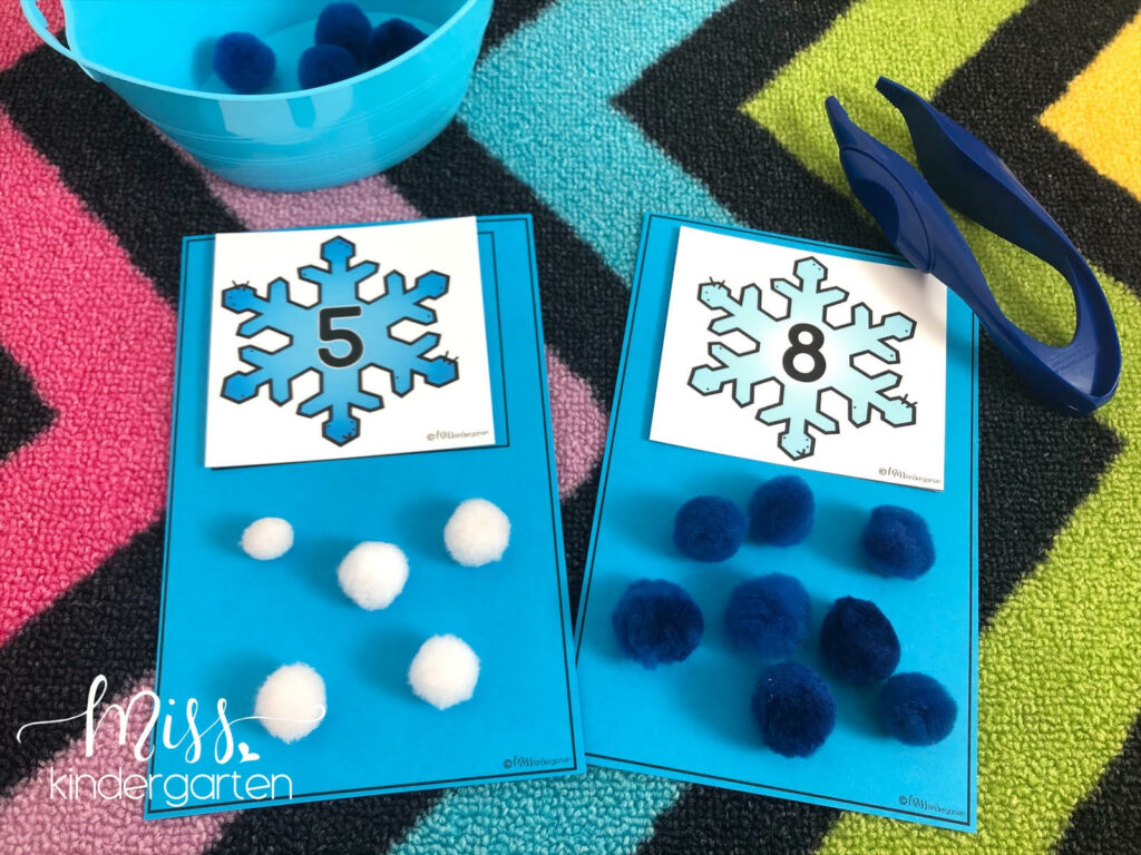 Adding pom poms to two snowflake counting mats