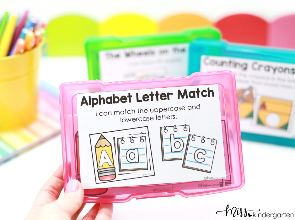 Holding a plastic storage box with Alphabet Letter Match center activity