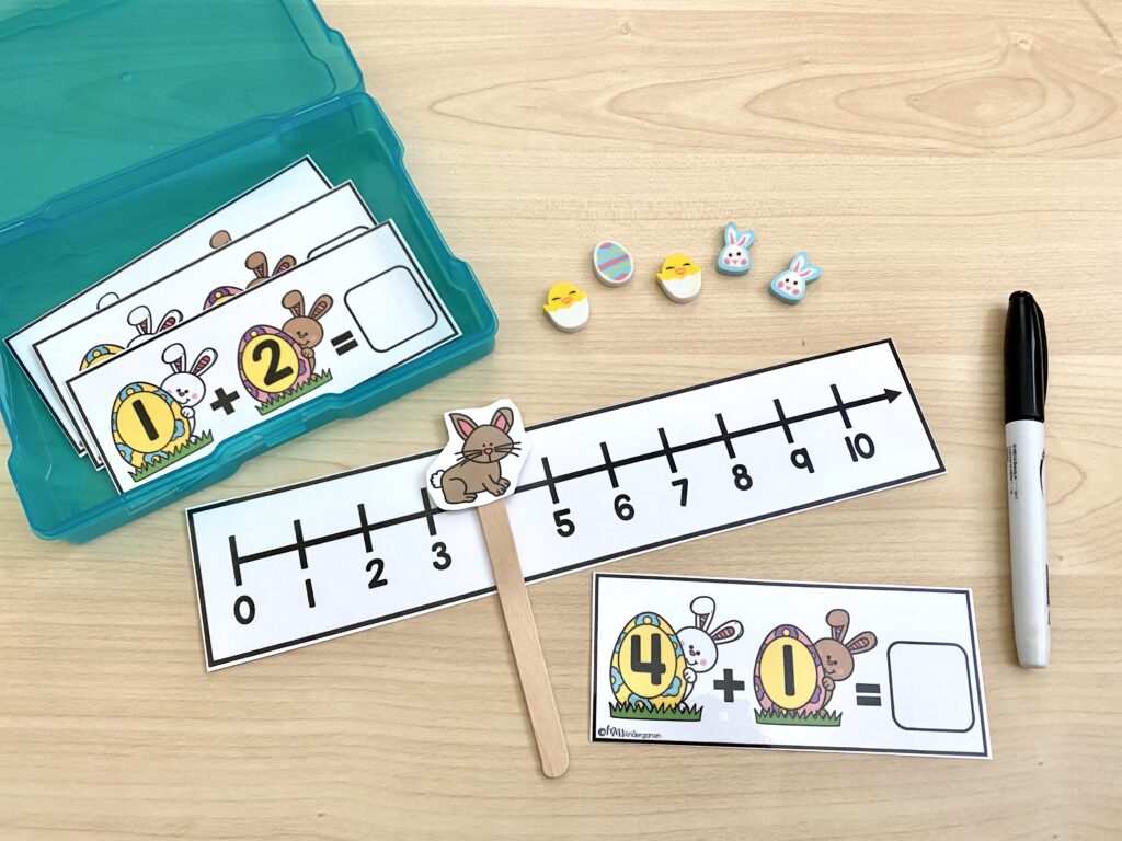 Addition with a number line task card is being used with a paper bunny attached to a popsicle stick, along with mini eraser manipulatives.