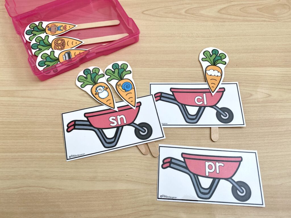 Paper carrots on popsicle sticks are being sorted into wheelbarrows with consonant blends.
