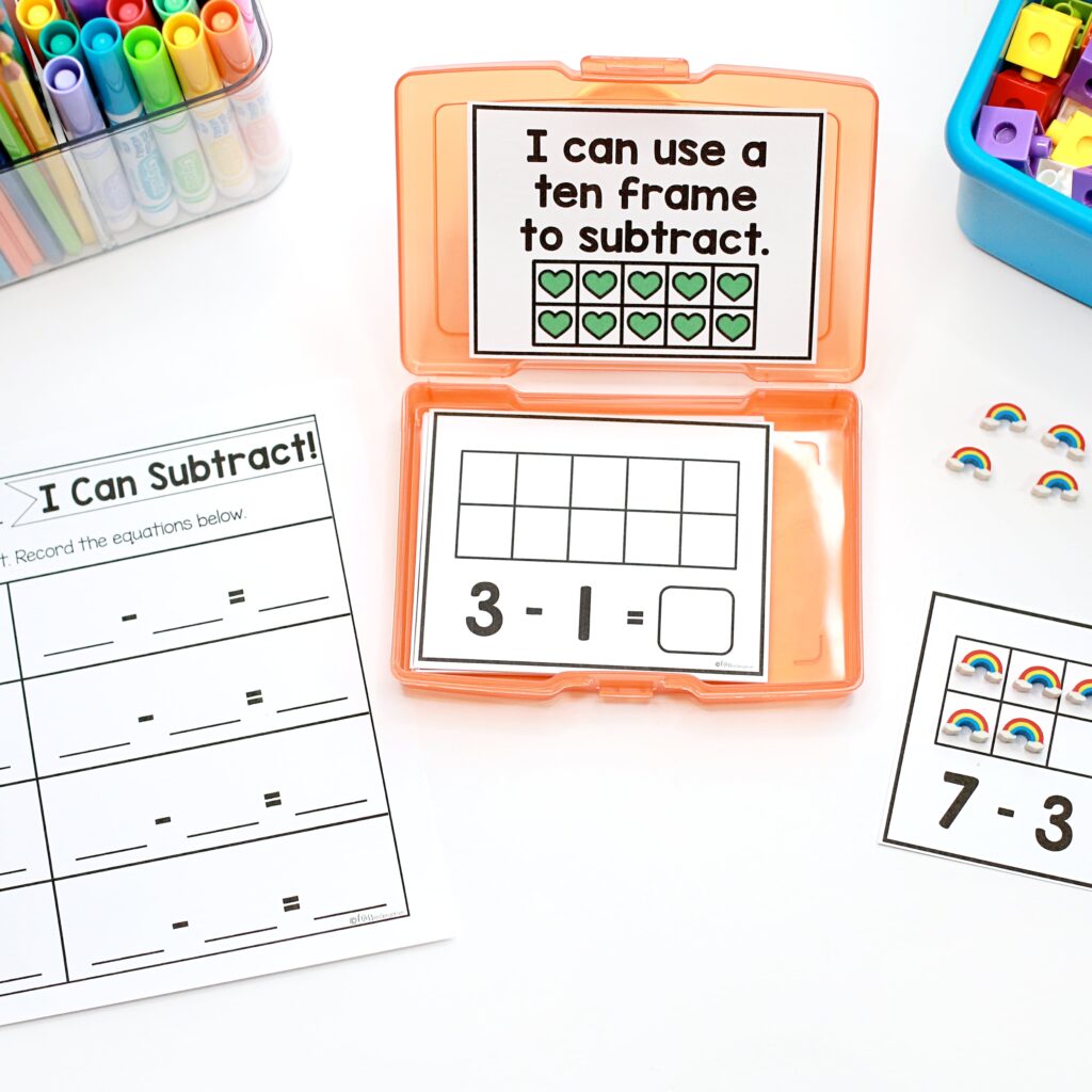 Ten Frame subtraction task cards are being used on a white desk top, along with a recording sheet.