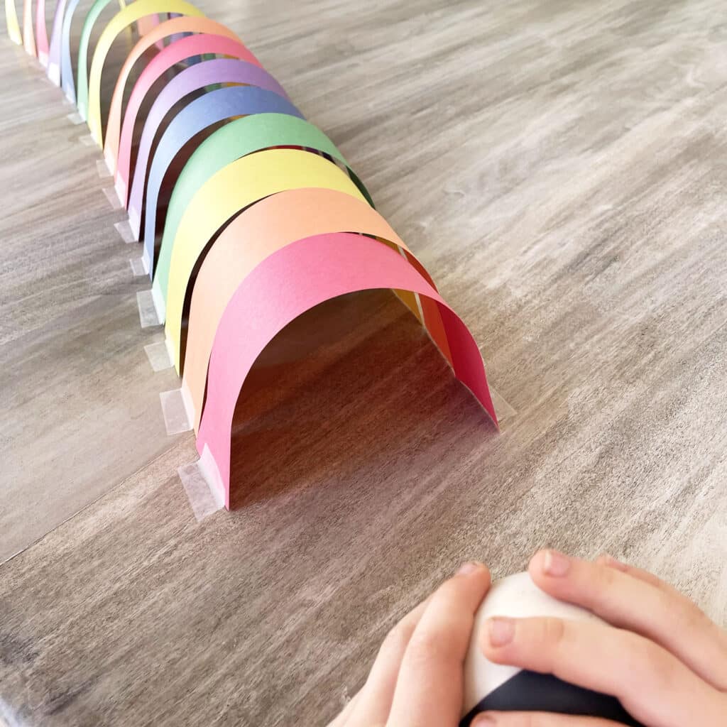 Getting ready to roll a ball into a rainbow tunnel.