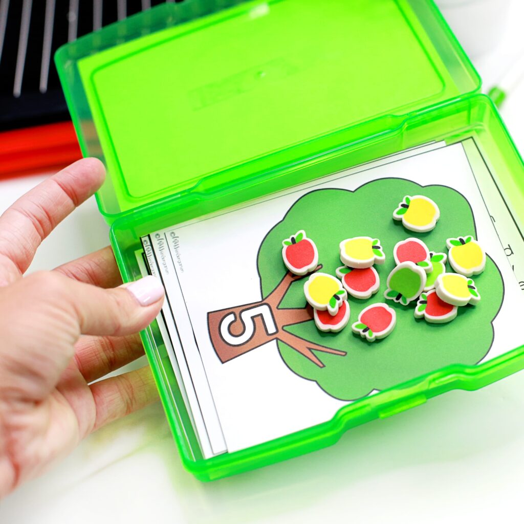 A photo storage box with apple tree task cards and apple mini erasers.