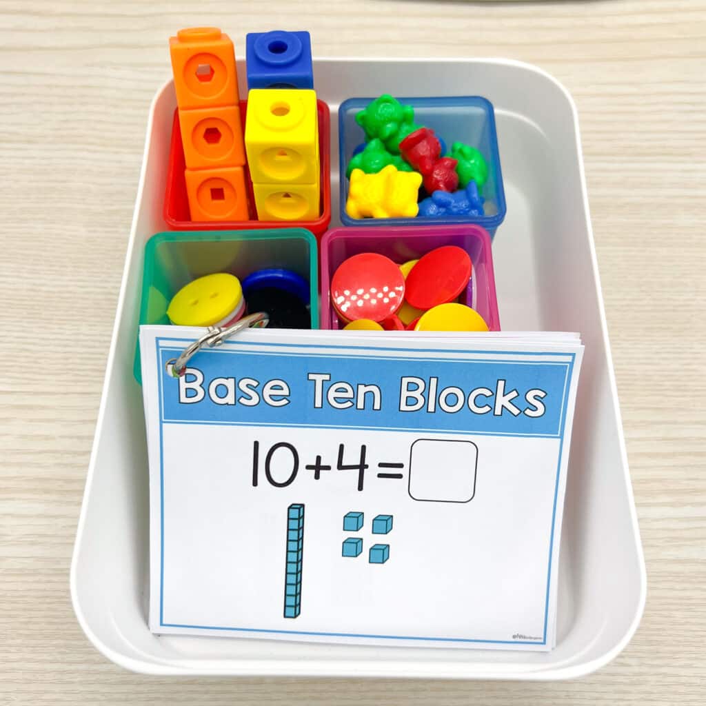 A binder ring of mini math strategy posters sits in a bucket of manipulatives